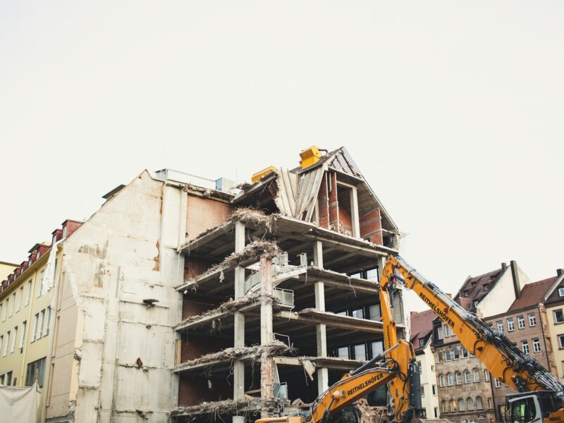 crane bull dozing a white concrete multi-storey building