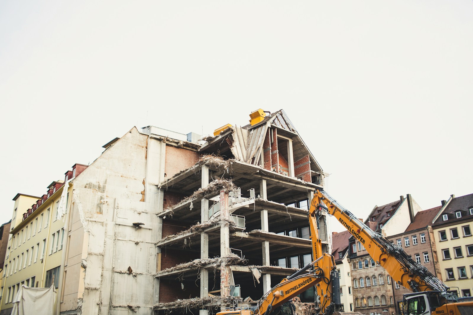 crane bull dozing a white concrete multi-storey building