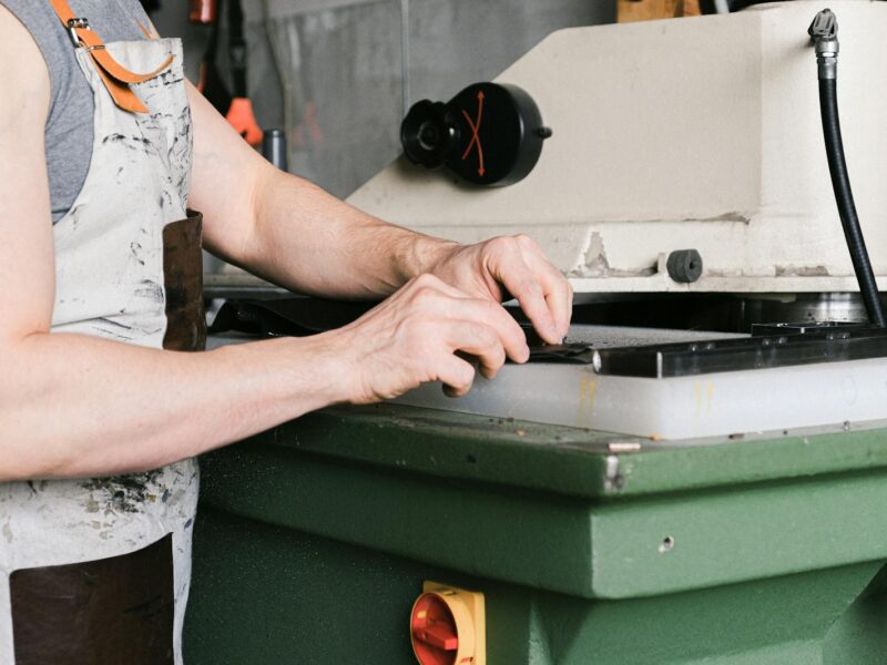 Close-up of man operating machinery in an industrial setting, wearing an apron.